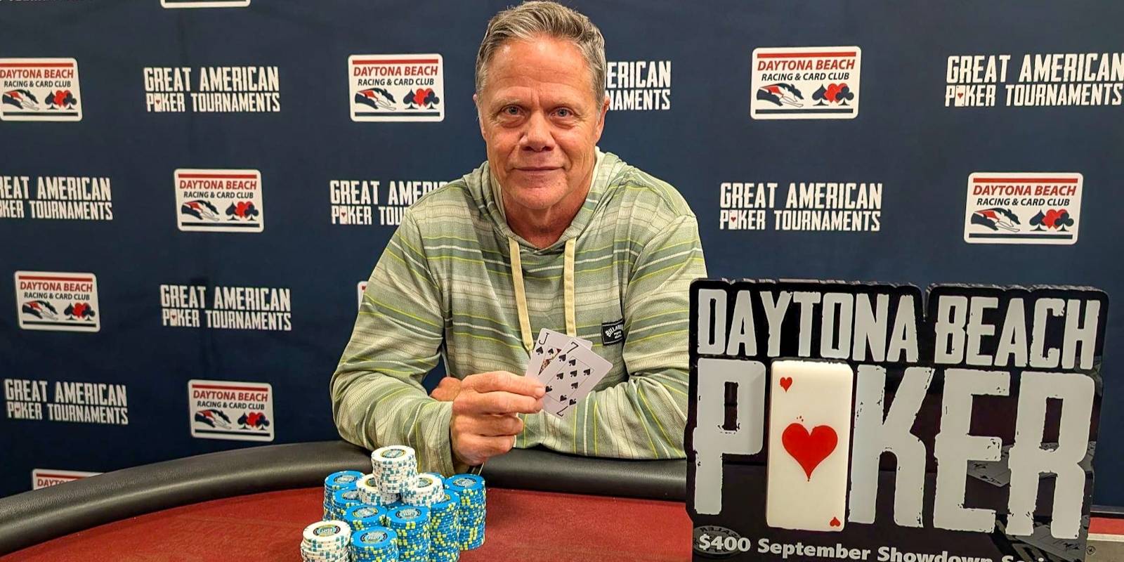 A person sitting at a table with poker chips in front of a sign that says daytona beach poker