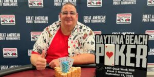 A person sitting at a table with a poker chips and a sign that says daytona beach poker