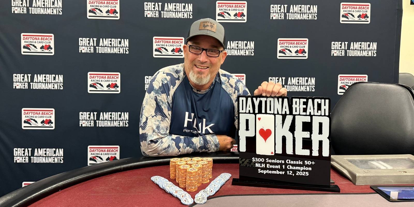 a person sitting at a poker table with a trophy and poker chips in front of him