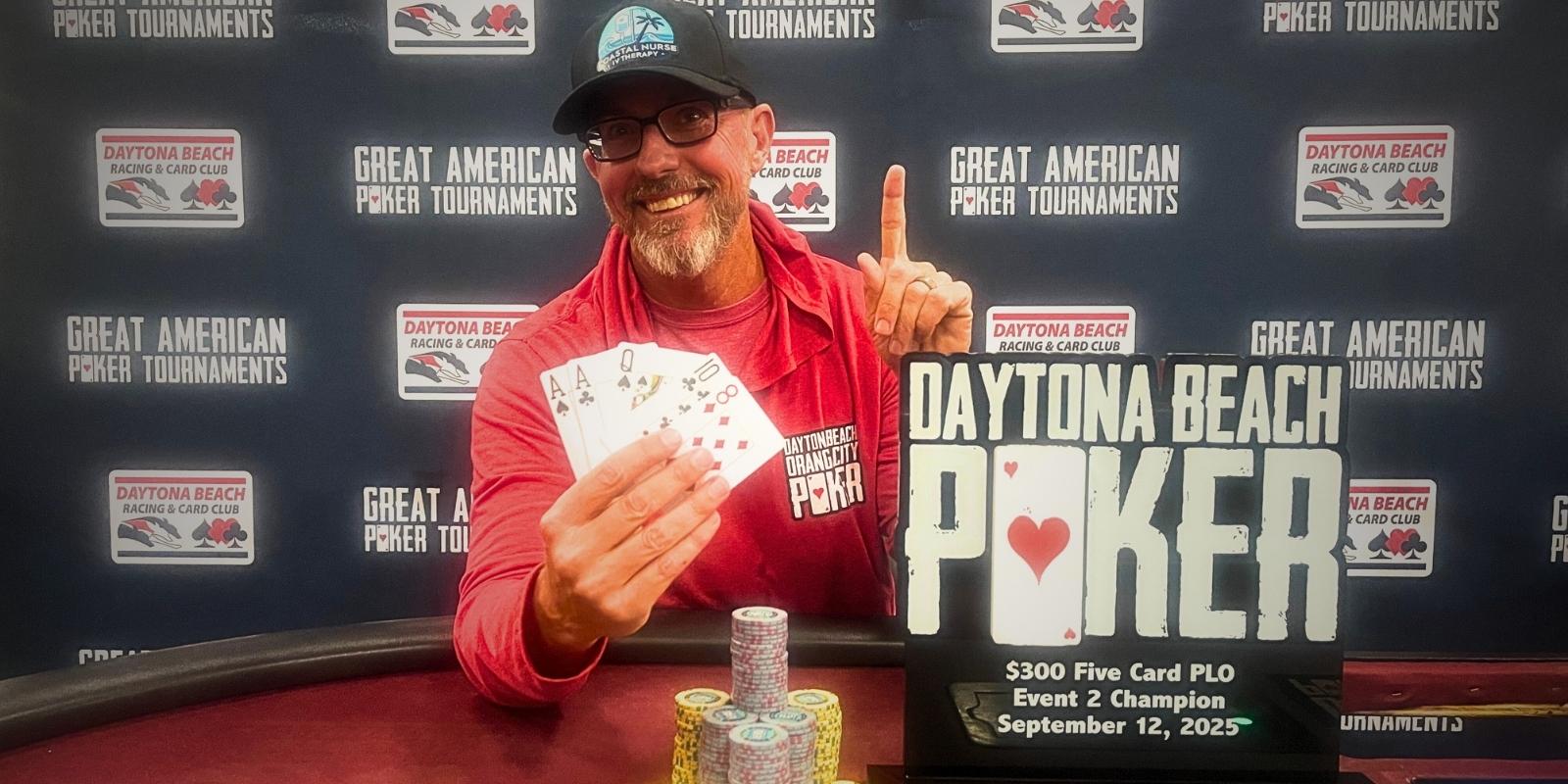 A person holding up five cards in front of a sign that says daytona beach poker