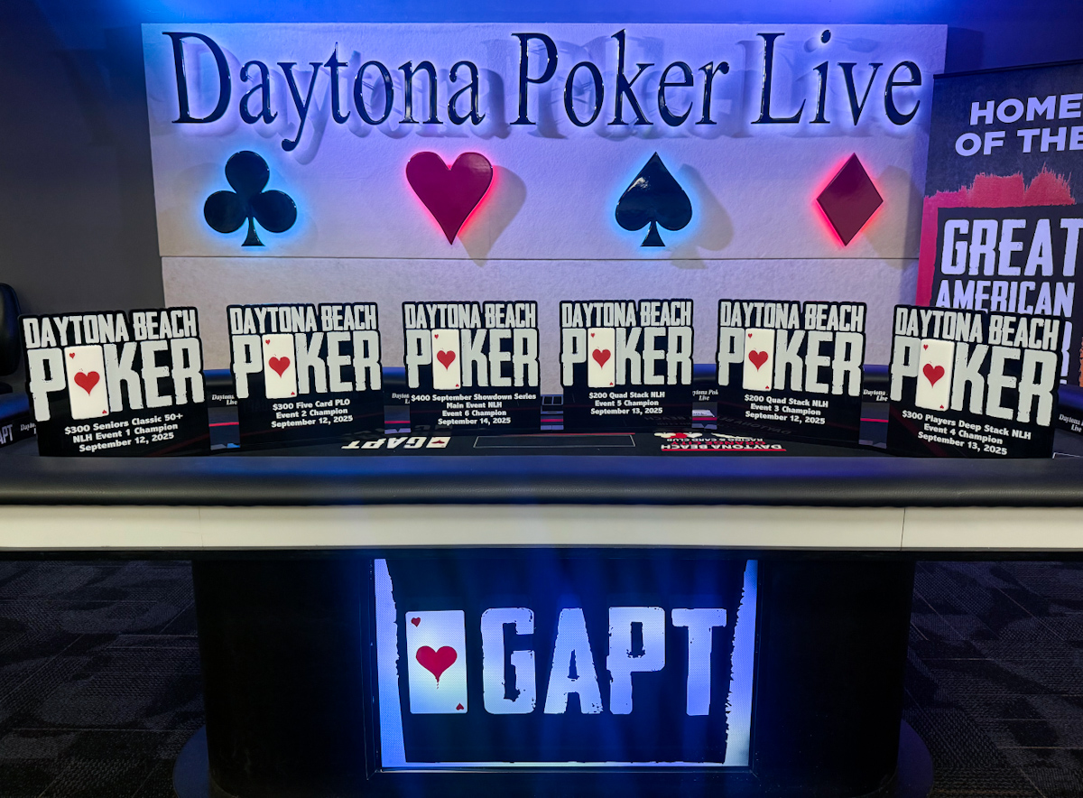 Six poker trophies lined up on a livestream table