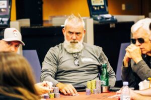 Poker player with white beard stares at his competition.