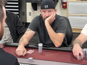 With a backwards UnderArmor hat Jonathan Preservati sits at a poker table hand over mouth.