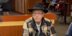 Thomas Dawson sits with cowboy hat and flannel jacket.