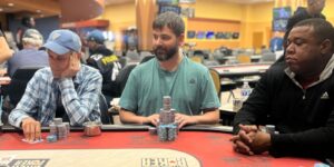Joshua Mordenti sits at a poker table with a green t-shirt.