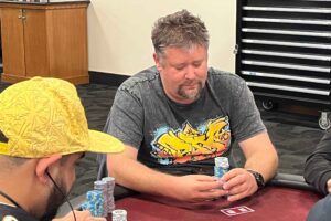 Nathan Helmick plays poker at a red table.