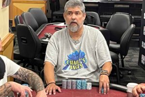 George Hortelano sits at a poker table with a "Charlies Angels" shirt.